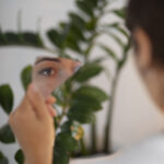 portrait young woman with low self esteem looking hand held mirror